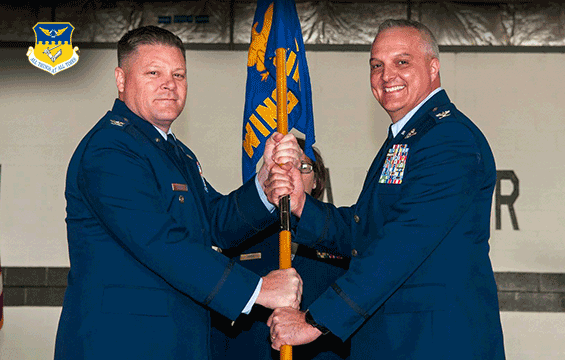 Two commanders pose holding the flag in between them