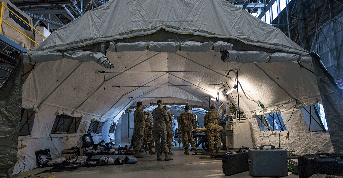 Medical group inside tent set up in hangar for training.