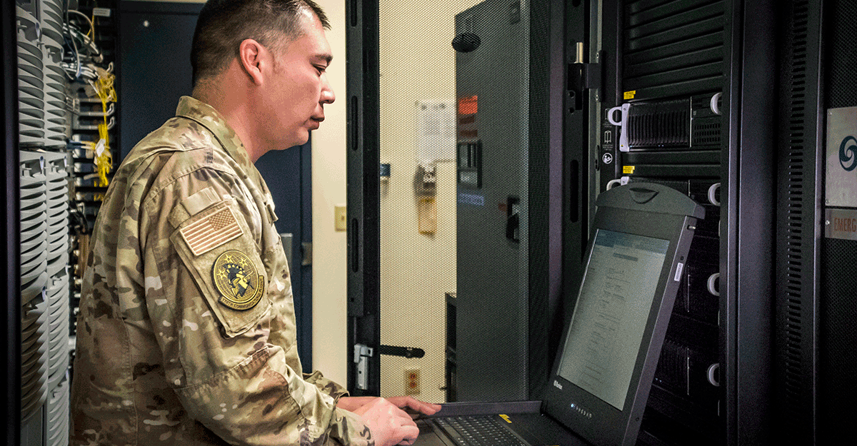 Airman at laptop in server room.