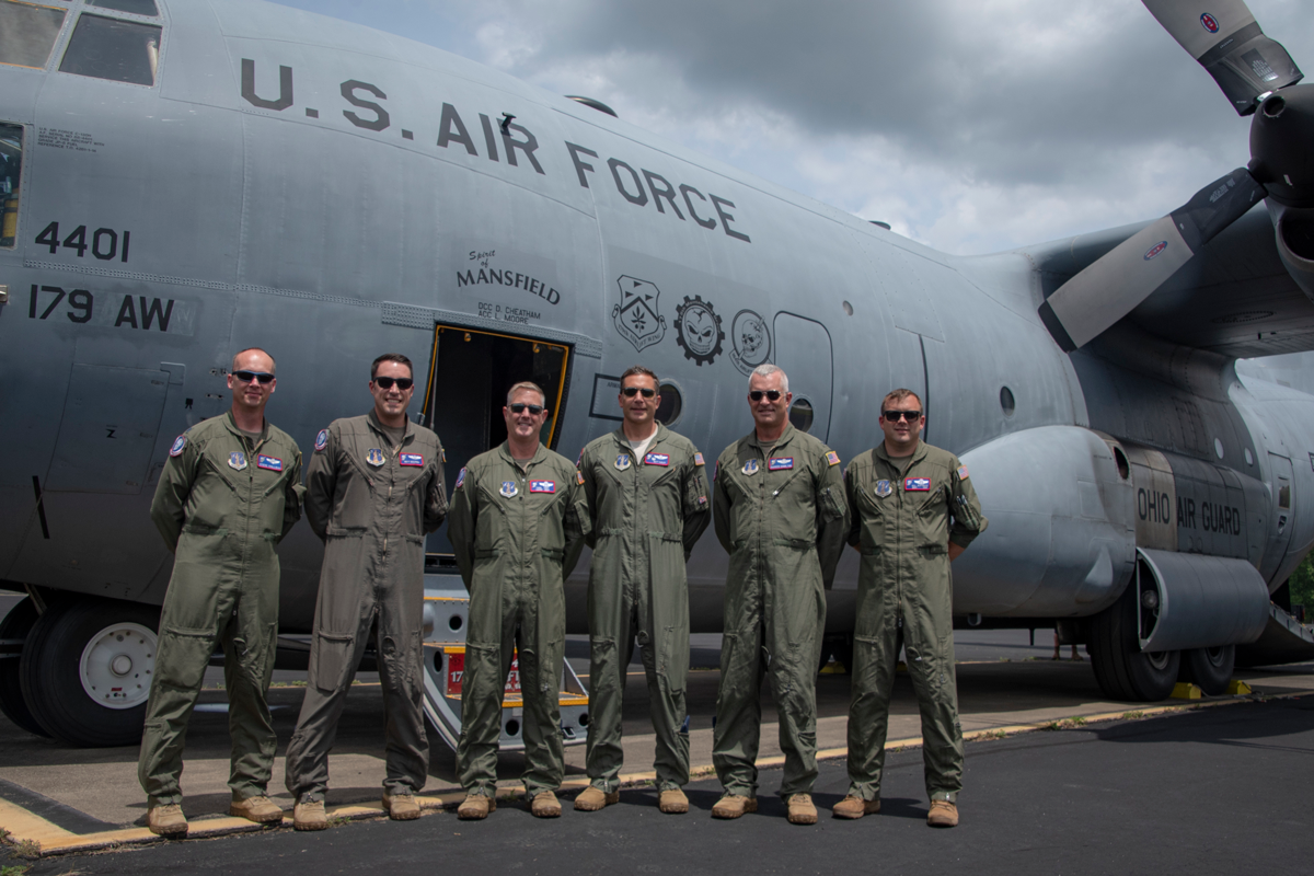 Crew stands in front of a C-130 .