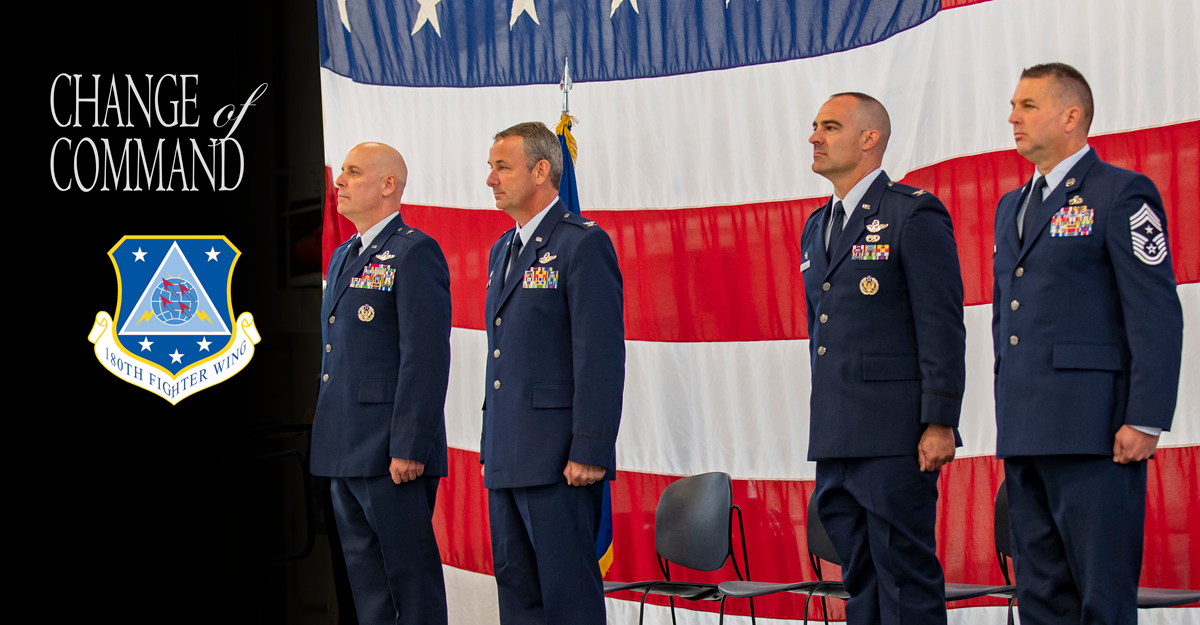 Air command stand at attention in front of American flag.
