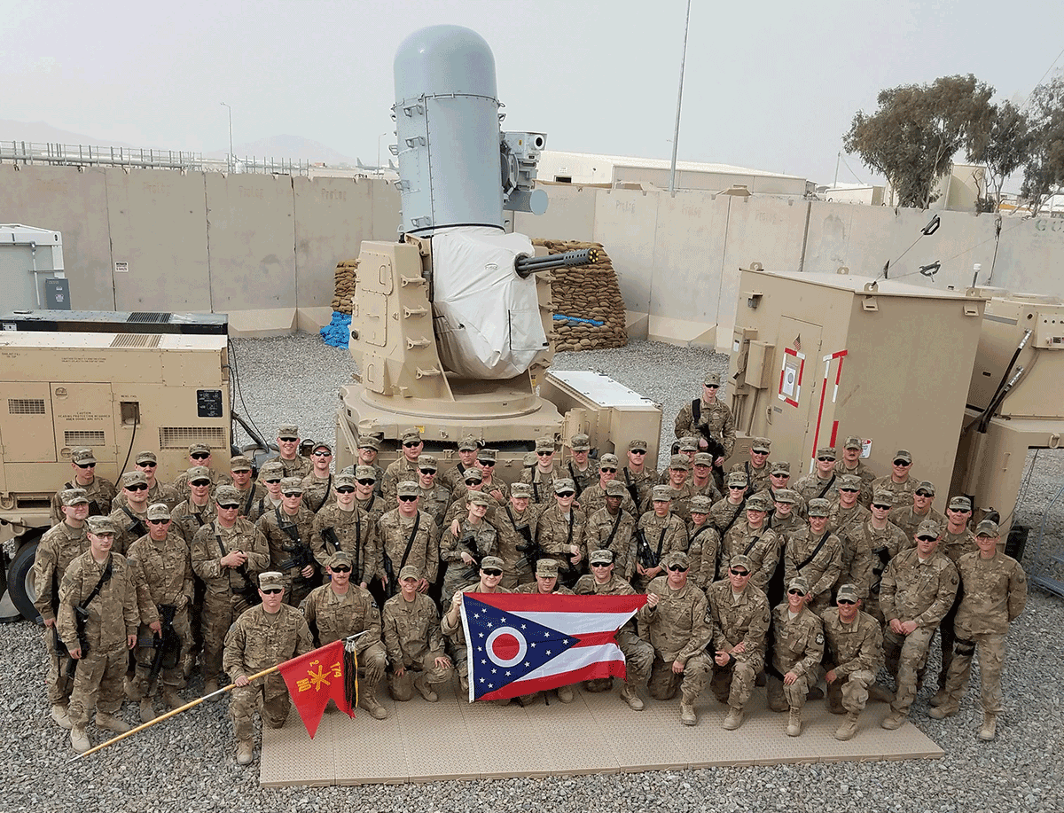 Airmen and Soldiers take a group photo in front of one of the Army's Counter-Rocket, Artillery and Mortar (C-RAM) Intercept weapons systems. 