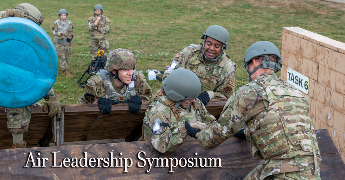 Airmen assist airmen going over wall in obstab=cle course.