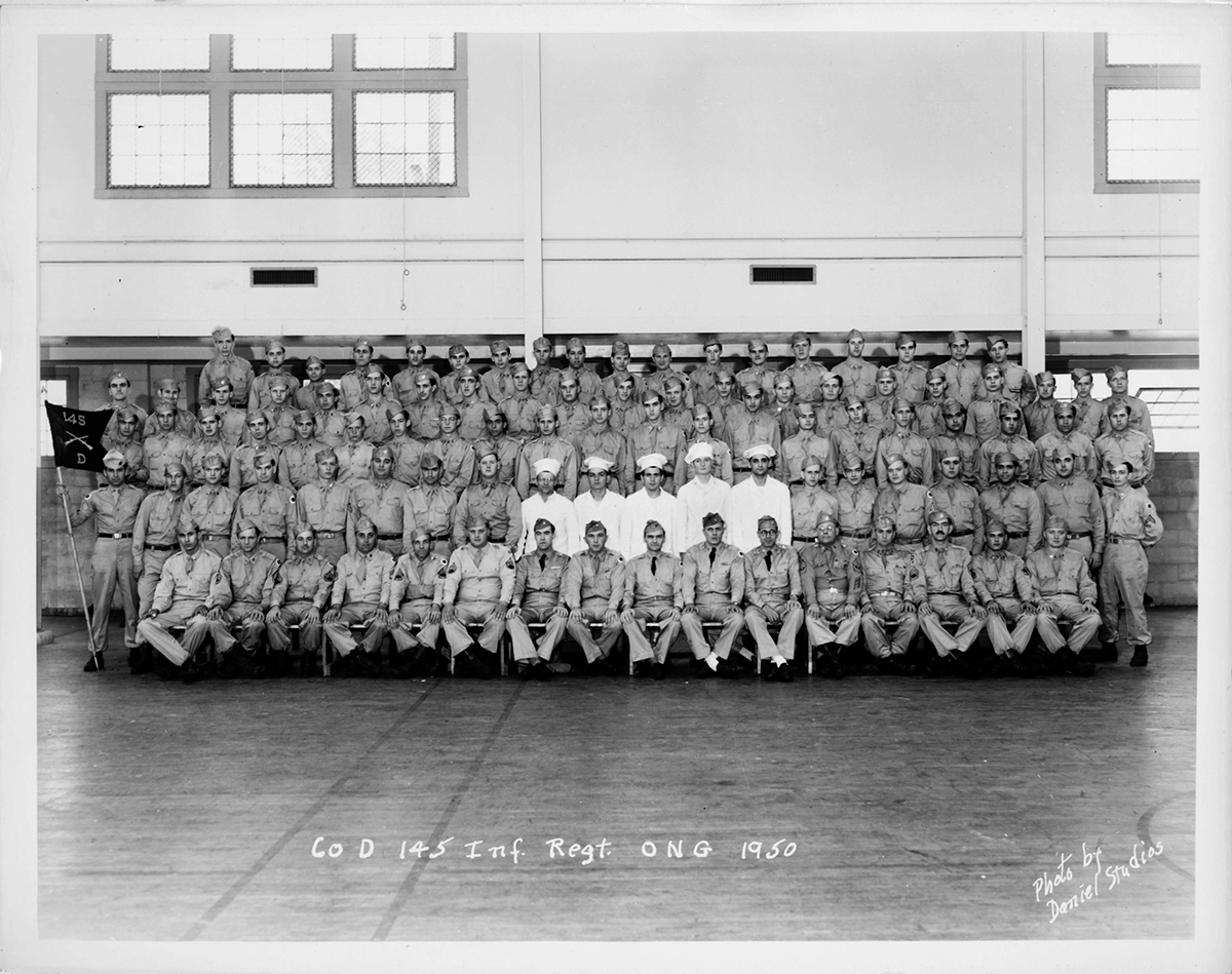 Black and white photo of group inside armory