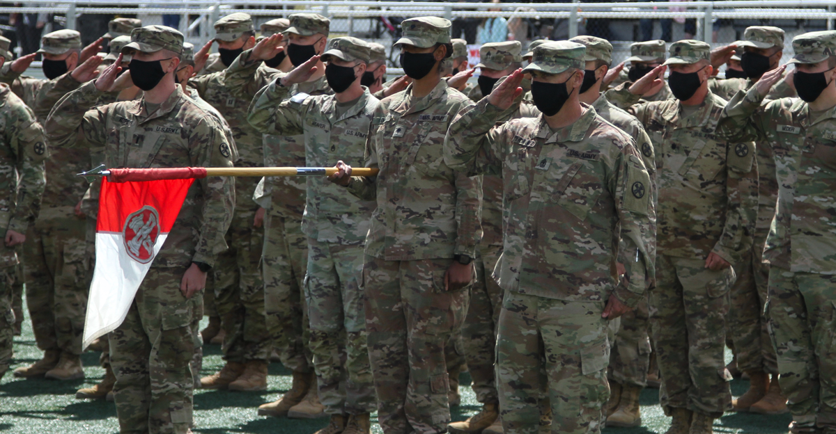 Soldiers stand in formation holding guidon.