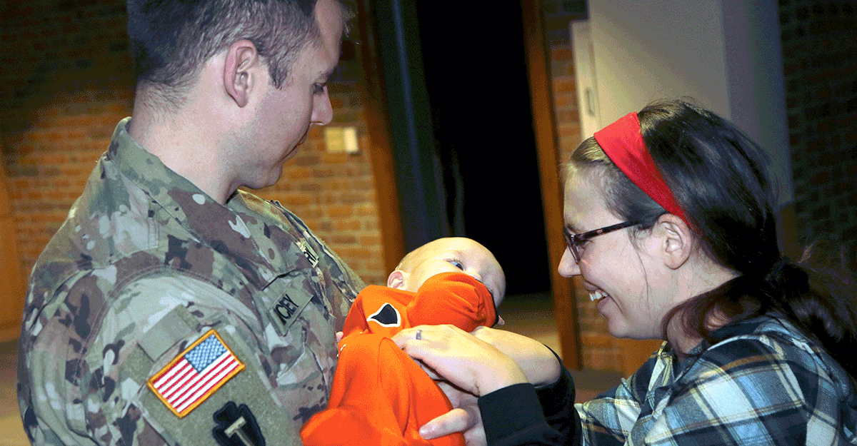 Soliders holds infant with mother.