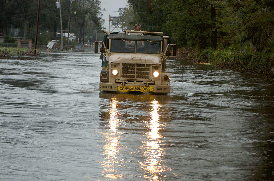 Truck driving through flooded street.
