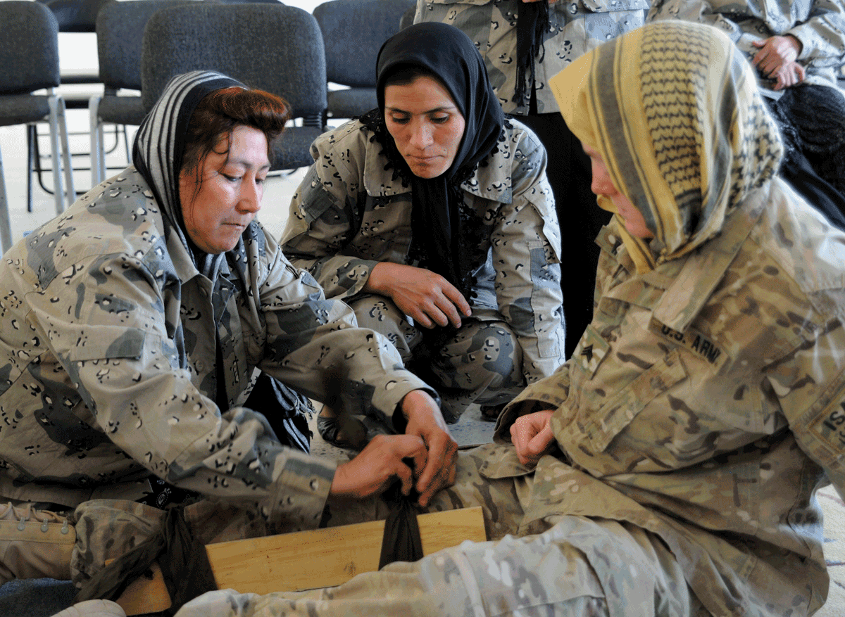 Three female soldiers on floor splinting a leg. 