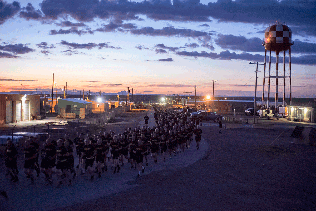 Hundreds of Soldiers in ARMY tshirts run at dawn on road through Fort Bliss.