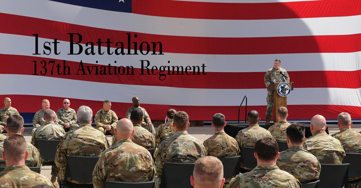 Col Shank addresses Soldiers from podium in front of American flag.
