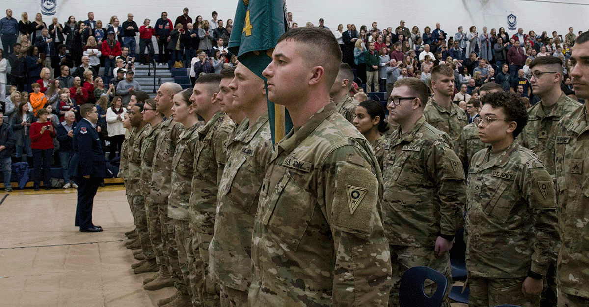 Soldiers stand at attention in gym.