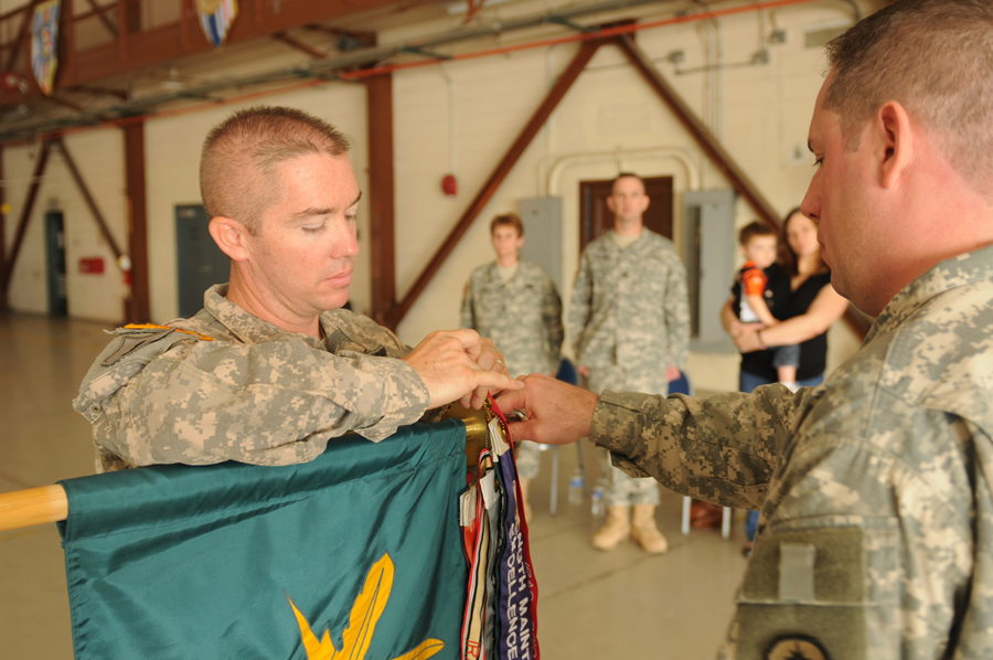 Color photo of Soldiers adding streamer to guidon.
