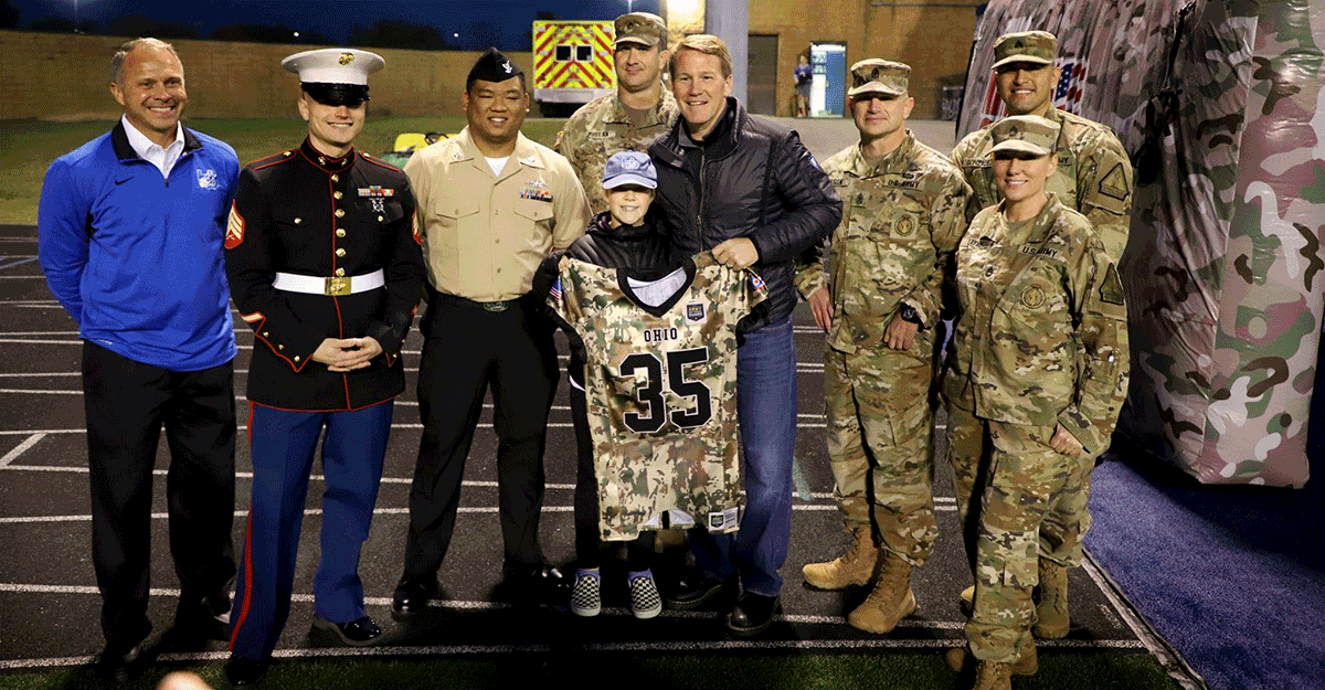 Lt. Gen. Husted with daughter and military memebrs on track. Daughter holding up Guard jersey