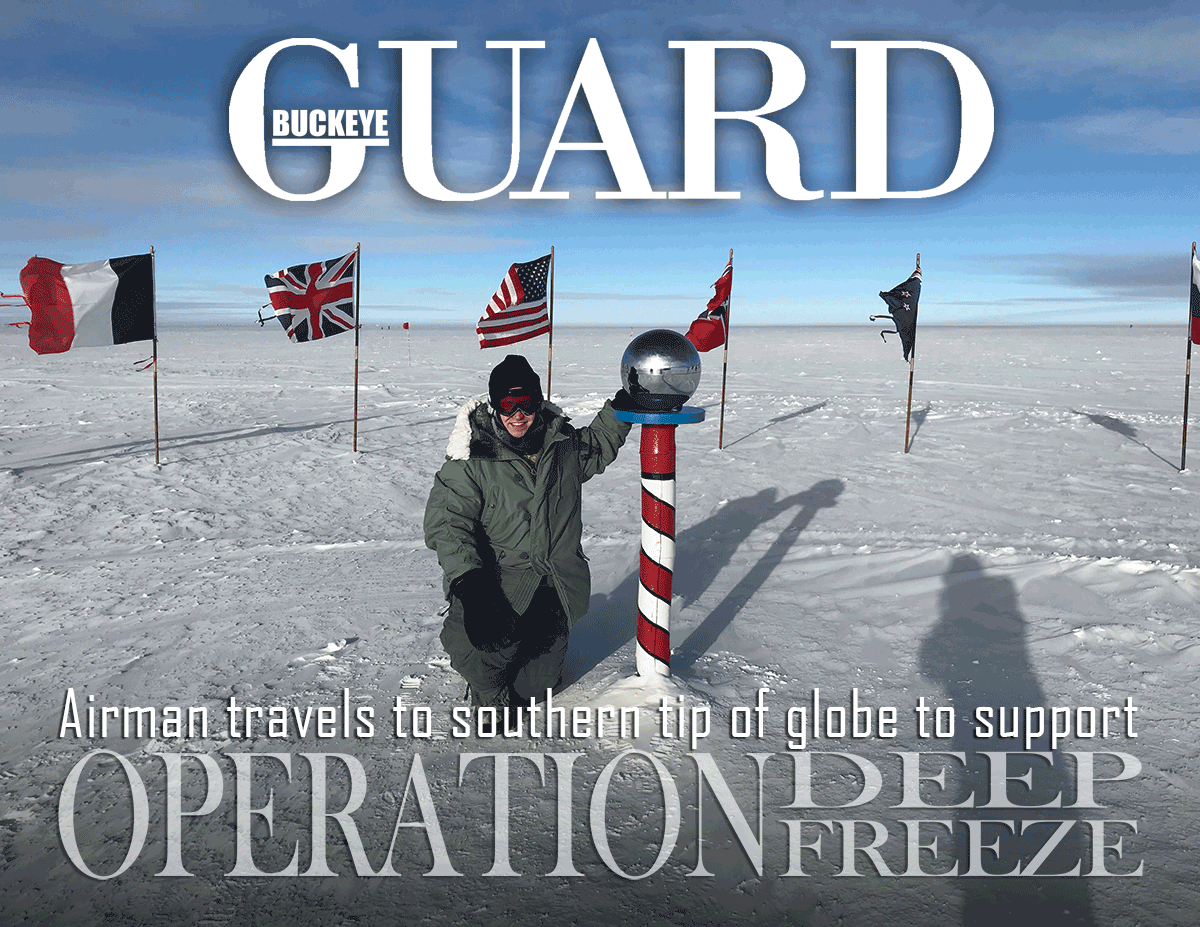 Airman kneels at north pole with country flags surrounding in back
