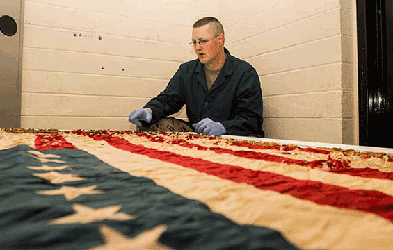 Sgt. 1st Class Joshua Mann, Ohio Army National Guard historian, looks over flag from the historical archives.