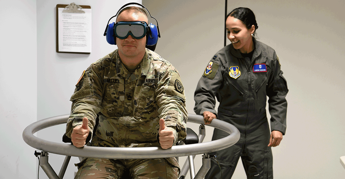 Soldier sitting inside ring with headset and virtal reality goggles.