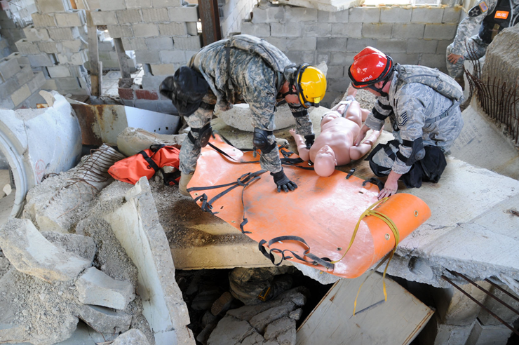 Guard members work on rescue dummy in rubble during training.