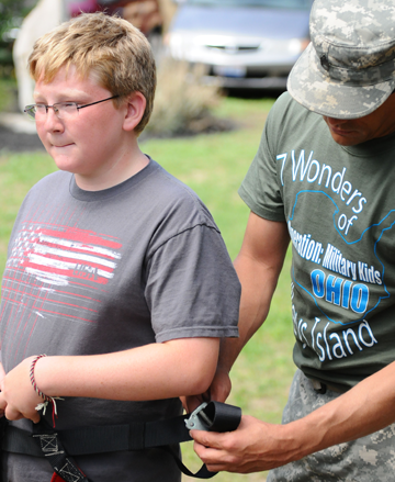 Sgt. Doug Montgomery, of Company D, Ohio  Army  National Guard Recruit Sustainment Program, helps Ian Manahan tighten a climbing harness in preparation to scale a climbing wall