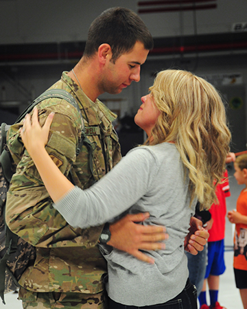 Senior Airman Tyler Newell embraces his wife in the hangar of the 180th Fighter Wing after returning from a deployment.