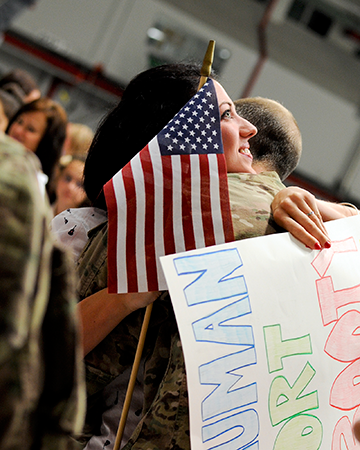 A loved one hugs Tech. Sgt. Dustin Bauman, a fuel shop technician, for the first time in over two months.  