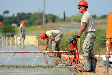 Master Sgt. Joe New, a structures technician with the 200th RED HORSE Squadron operates the concrete screed machine to level concrete as it is poured for multipurpose building foundations.