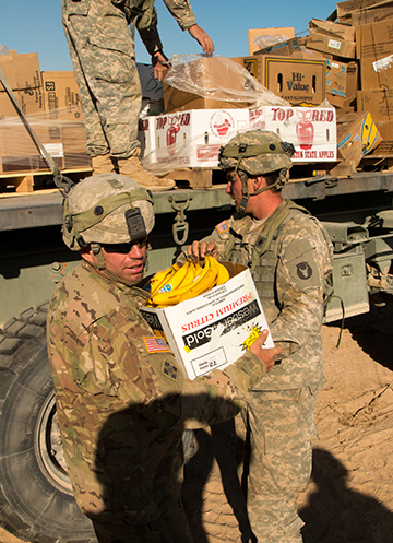 Soldiers of the 1st Battalion, 145th Armored Regiment unload fresh produce from a logistical supply convoy.