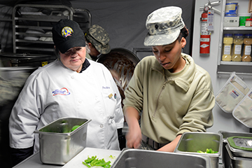 Joan Elliot-Wagner (left), an evaluator from the National Restaurant Association, observes Spc. Deshaunna Gee.