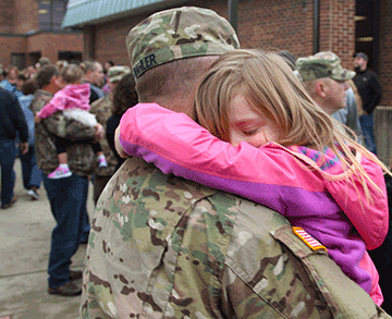 Chief Warrant Officer 2 William Wahler, a systems integrator, hugs his daughter after the ceremony.