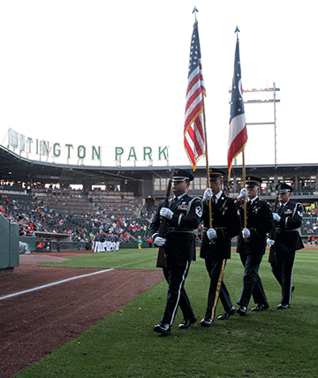 Soldiers and Airmen composing an Ohio National Guard joint color guard return from the field after displaying the flags during the national anthem.