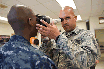 Tech. Sgt. Luis Torres (right) uses an auto refractor to determine prescription.