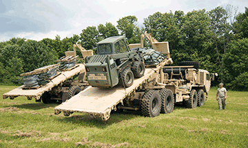 Two Ohio National Guard M1075 palletized loading trucks deliver construction materials to members of Headquarters, 216th Engineer Battalion.