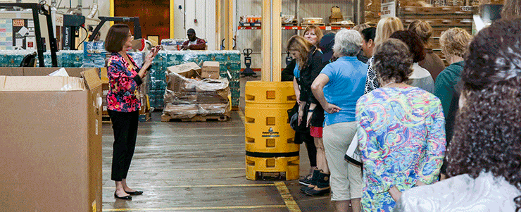Spouses of state adjutants general from across the country are careful to stay within the yellow lines to keep clear of the many forklifts loading and unloading items at the Mid-Ohio Foodbank.