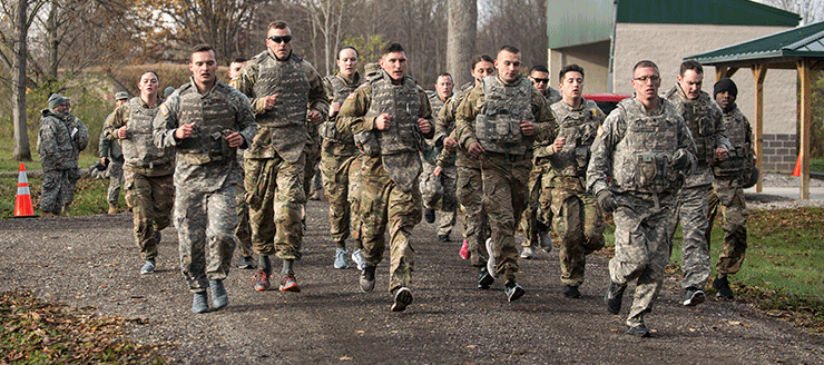 Soldiers running in full gear along path.