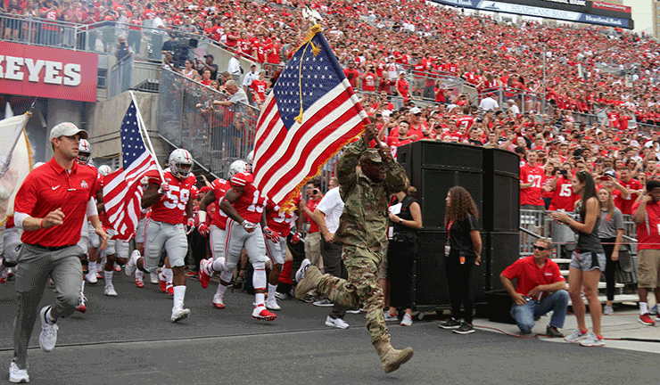 Sgt. John Siler, a personnel noncommissioned officer with the 174th Air Defense Artillery Brigade and Purple Heart recipient, leads The Ohio State University football team onto the field.