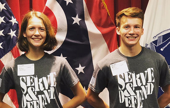 Brother and sister stand in Serve and Defend t shirts.