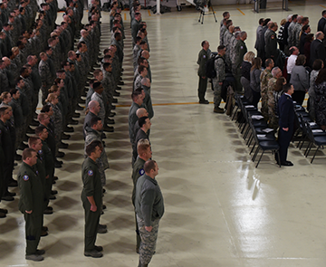 Members of the 179th Airlift Wing stand at attention in balcony shot in hangar.