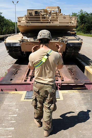 back of soldier guiding tank off train bed.