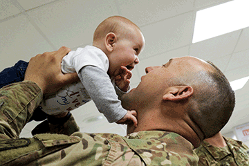 Soldier lift infant in air.