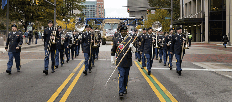Head on view of Members of the 122nd Army Band marching in the street.
