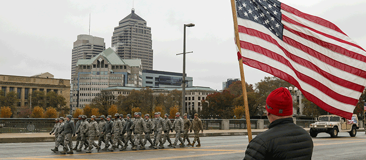 Airmen of the 121st Air Refueling Wing march past spectators waving American flags.