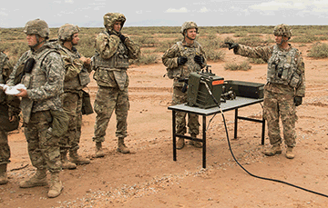 Soldiers stand around a table on missle range.
