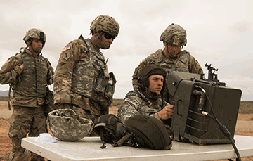 Four soldiers around a table on missle range looking at screen.