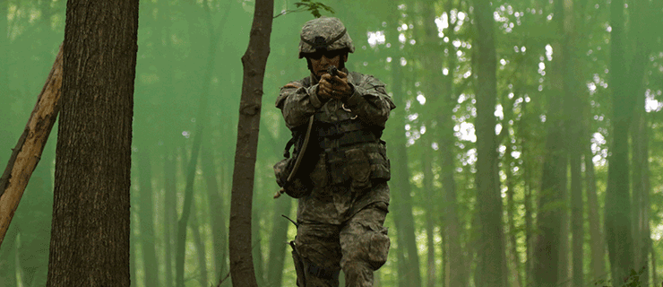 Soldier running through woods with weapon pointed