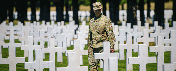 Soldier stands alone among sea of crosses.