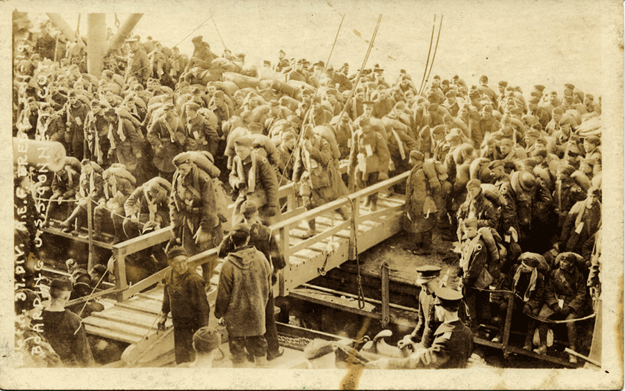 Sepia-tone photo of Soldiers getting on ships.