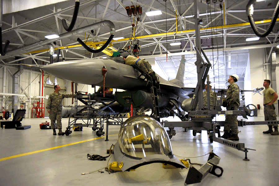 Airmen work on F-16 inside hangar with