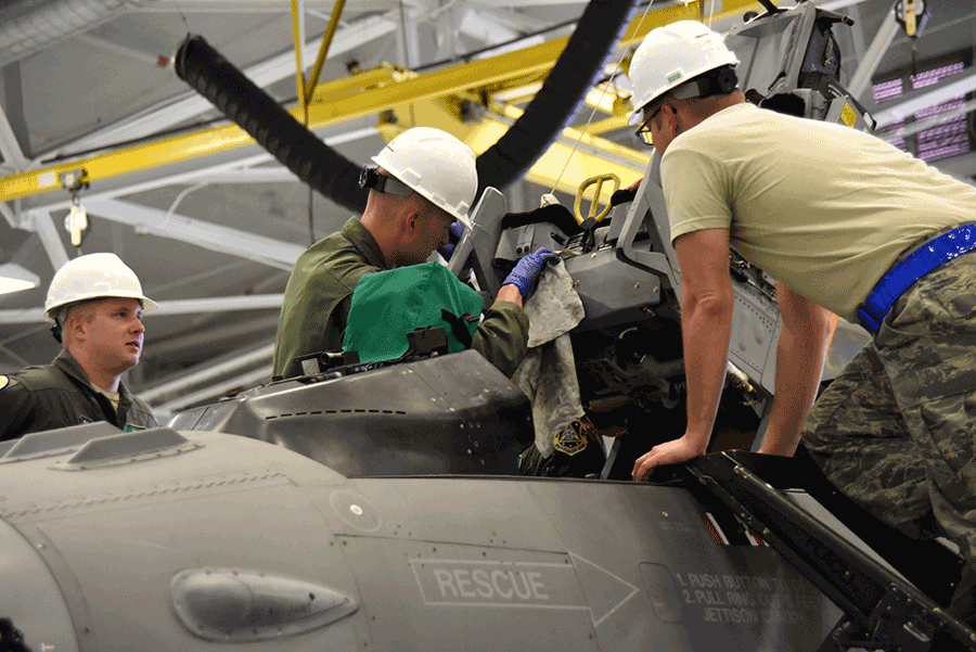 Close up of Airmen working on F-16 inside hangar.