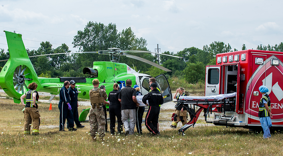Soldiers and EMS transport simulated causuality from truck to helicopter.