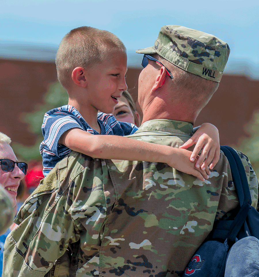 Uniformed Soldier holds son.