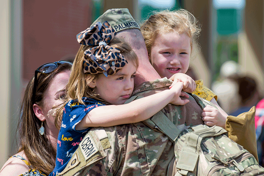 Uniformed Soldier holds his daughters.